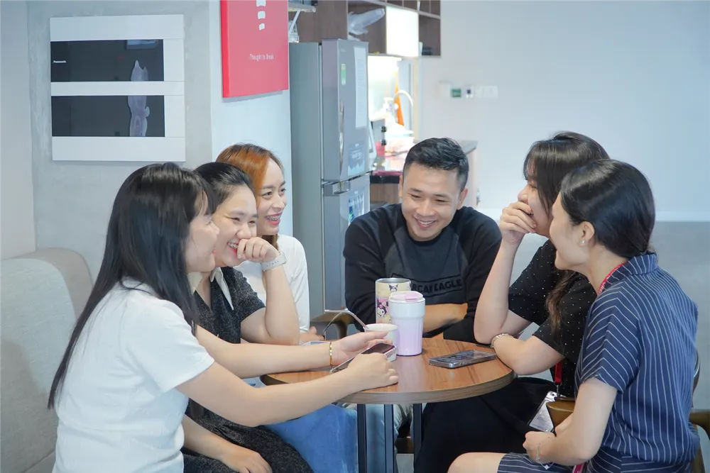 Hình ảnh trong văn phòng Home Credit, nhân viên đang trao đổi công việc trong không khí vui vẻ..png