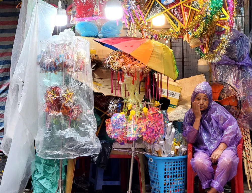 Bà Lan (70 tuổi), chủ cửa hàng lâu năm trên phố Hàng Mã than: "Mưa to, bán vất vả lắm. Lượng khách giảm đi một nửa, tồn nhiều hàng...". Ảnh: HÀ NGUYỄN
