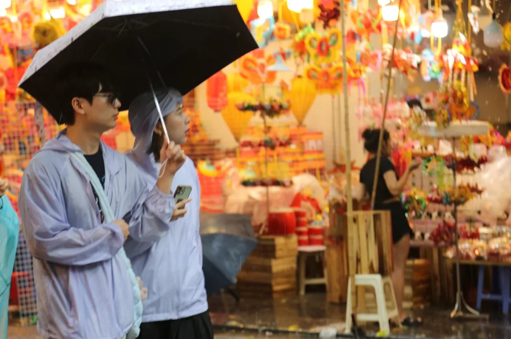 Người đi mua hàng rất ít, thi thoảng có một vài bạn trẻ đội mưa dạo qua ngắm nghía rồi vội vã rời đi. Ảnh: HÀ NGUYỄN