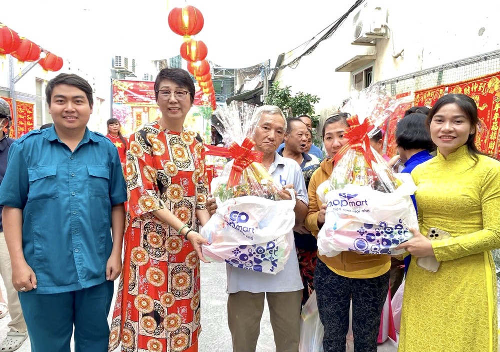 唐金萍女士（左二）与坊、街区代表向群众发送春节礼物。