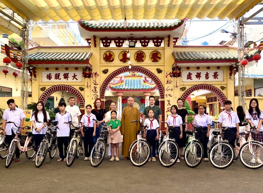 释慧功和尚和邓栢荣家眷向孤儿学生赠送自行车。