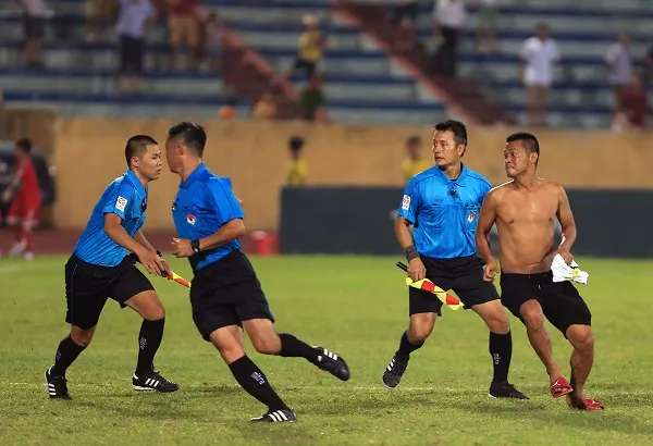 Các trợ lý trọng tài nỗ lực ngăn cản khán giả chạy vào sân. Ảnh: MINH HOÀNG