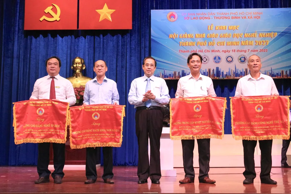 Ông Nguyễn Văn Lâm, Phó Giám đốc Sở LĐTB-XH TPHCM (giữa), trao cờ cho hiệu trưởng 4 hội đồng thi. Ảnh: QUANG HUY