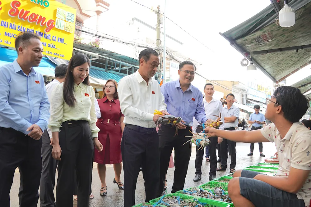 Đồng chí Huỳnh Thanh Nhân (thứ 3 từ trái vào) thăm hỏi hộ kinh doanh tại chợ hải sản Xóm Lưới. QUANG HUY