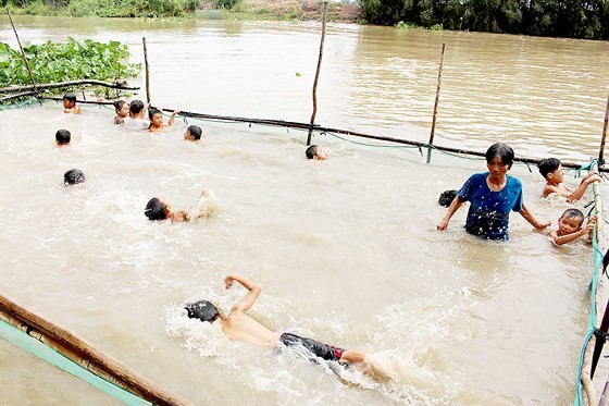 Mrs. Tran Thi Kim Thia is coaching kids in swimming.