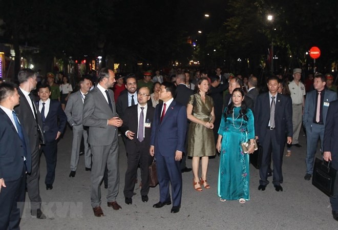 French Prime Minister Edouard Philippe and Chairman of Hanoi People's Committee talk during their walk around Hoan Kiem Lake (Photo: VNA)