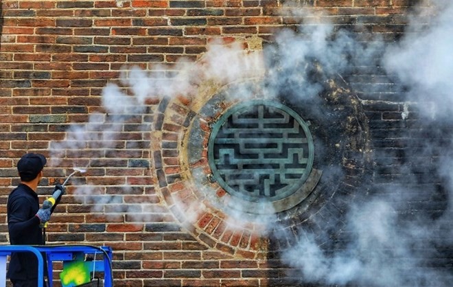 Many of the nearly 200-year-old gate's bricks (L) have regained their bright red color after 15 days. (Photo: vnexpress.net)