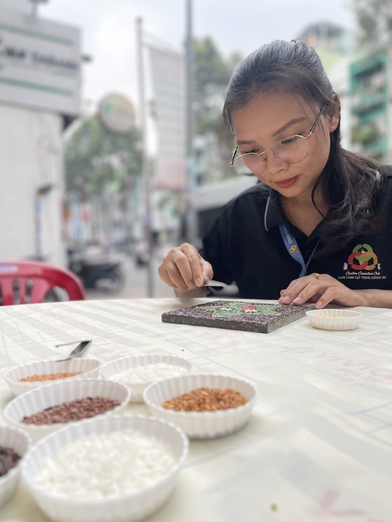 A visitor learns about making a rice painting at Quynh Vy rice painting workshop. (Photo: SGGP)