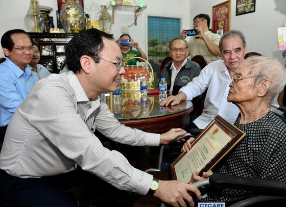 Mr. Nguyen Van Hieu hands over State President Nguyen Xuan Phuc’s greeting card to Ms. Nguyen Thi Gan, to wish her good health and long life on her 100th birthday. (Photo: SGGP)