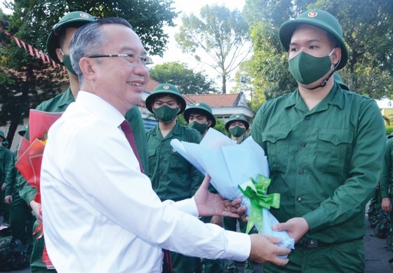 Director of the HCMC Department of Culture and Sports Tran The Thuan offers flowers to young men at the ceremony to send off new recruits for military in Binh Thanh District. (Photo: SGGP)