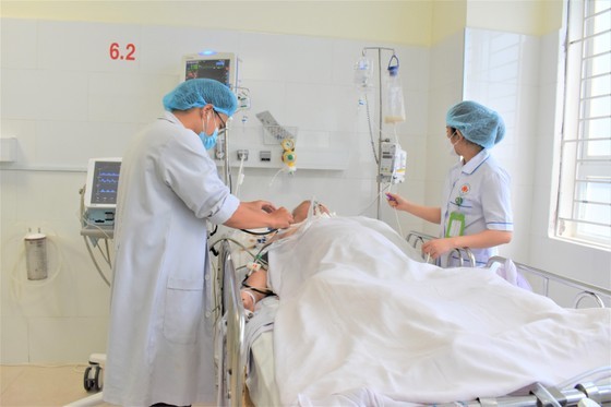 Dr. Lam Kim Bao (L), head of the Department of Intensive Care and Anti-Poison of Nguyen Trai Hospital, gives a checkup to a patient. (Photo: SGGP)