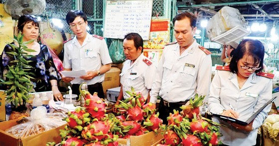 Inspectors from the city’s Food Safety Management Board check food safety at a booth in a market in Thu Duc Agricultural Wholesale Market. (Photo: SGGP)