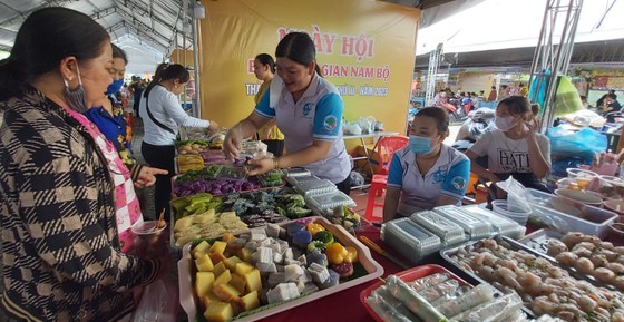 Visitors enjoy folk cakes at a stall in the festival. (Photo: SGGP)
