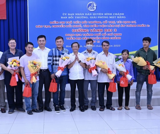 Deputy Director of the HCMC Department of Natural Resources and Environment Vo Trung Truc (5th, R) and Chairman of the People’s Committee of Binh Chanh District Vo Duc Thanh (3rd,L) offer gifts to affected families. (Photo: SGGP)