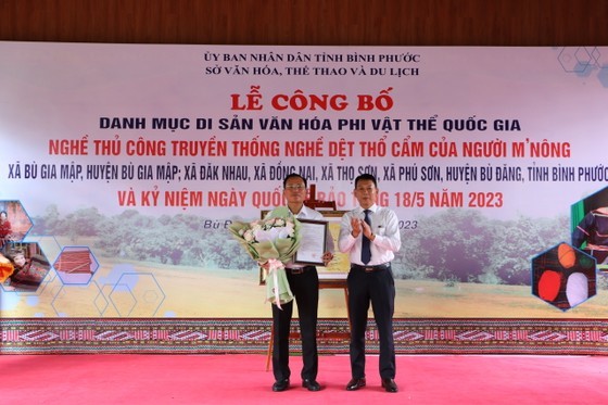 A representative of the Ministry of Culture, Sports and Tourism in HCMC offers a certificate of recognition and flowers Bu Dang District. (Photo: SGGP)