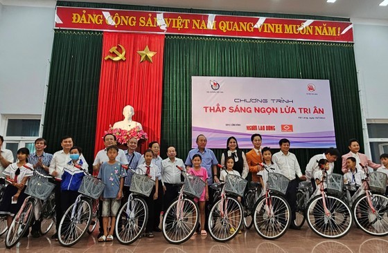 Former Deputy Prime Minister Truong Hoa Binh (C) hands over bicycles to disadvantaged students in Quang Tri Province. (Photo: SGGP)