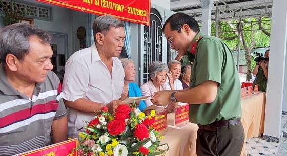 Deputy Director of the HCMC Department of Public Security Le Quang Dao hands over presents to families credited with revolutionary service at the security zone T4 in Vinh Loc A Commune of Binh Chanh District. (Photo: SGGP)