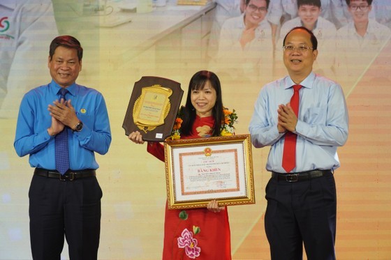 Vice Secretary of the HCMC Party Committee Nguyen Ho Hai (R) and Vice Chairman of the Vietnam General Confederation of Labour Huynh Thanh Xuan (L) congratulate a female engineer. (Photo: SGGP)