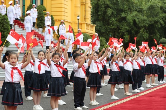Vietnamese students welcome Singaporean Prime Minister Lee Hsien Loong at the receiving ceremony. (Photo: SGGP)