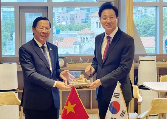 Chairman of the HCMC People's Committee Phan Van Mai (L) offers a gift to Mr. OH Se Hoon, Mayor of Seoul. (Photo: SGGP)