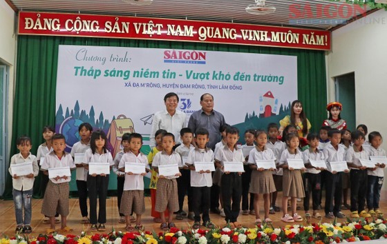 Editor-in-chief of the SGGP Newspaper Tang Huu Phong (L) and Vice Chairman of the People's Committee of Dam Rong District Lieng Hot Ha Hai offer scholarships to students of the Da M’rong primary school. (Photo: SGGP)