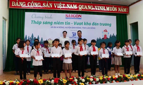 Deputy Editor-in-chief of the SGGP Newspaper Pham Truong (L) offers scholarships to students of the Da M’rong primary school. (Photo: SGGP)