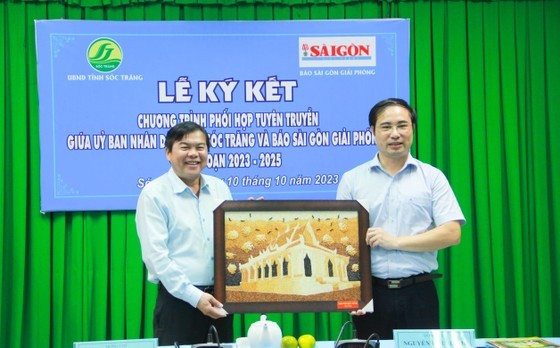 Director of the provincial Department of Information and Communications Nguyen Huu Hanh (R) offers a gift to Editor-in-Chief of the SGGP Newspaper Tang Huu Phong.