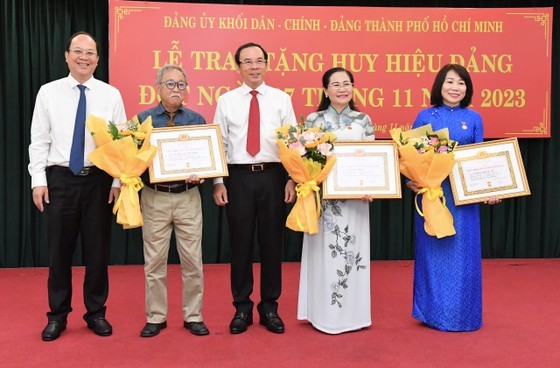 Secretary of the HCMC Party Committee Nguyen Van Nen (C) and Vice Secretary of the HCMC Party Committee Nguyen Ho Hai (L) award 30-year Party membership badges to Party members. (Photo: SGGP)