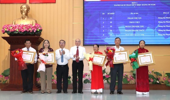 Head of the Propaganda and Education Board of the HCMC Party Committee Phan Nguyen Nhu Khue (C) attends a ceremony honoring 61 Party members with Party membership badges in District 8.