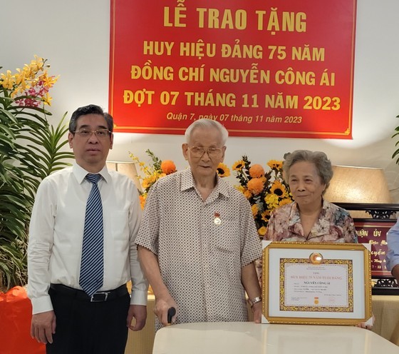 Vice Secretary of the HCMC Party Committee Nguyen Phuoc Loc (L) presents the 75-year Party membership badge to Mr. Nguyen Cong Ai, former Vice Chairman of the HCMC People’s Committee (C) in District 7.