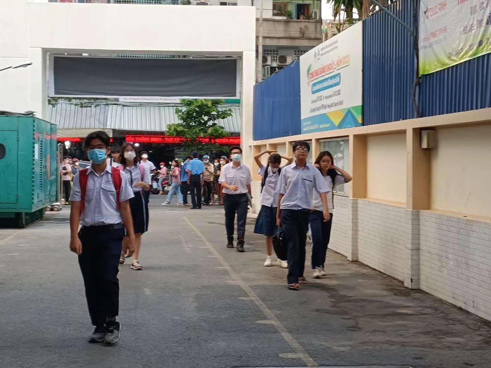 Học sinh di chuyển thành hai hàng từ cổng vào khu vực phòng thi