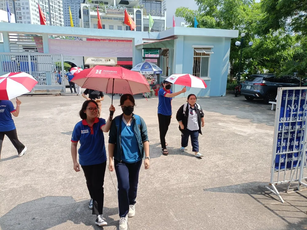 Tình nguyện viên hỗ trợ che nắng cho thí sinh tại điểm thi Trường THCS Đống Đa