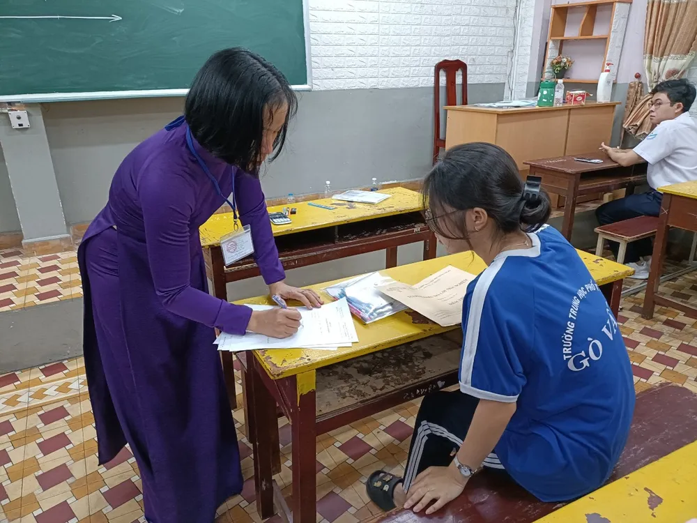 Thí sinh và cán bộ coi thi xác nhận bì thư đựng phiếu trả lời trắc nghiệm vẫn còn niêm phong. Ảnh: THU TÂM