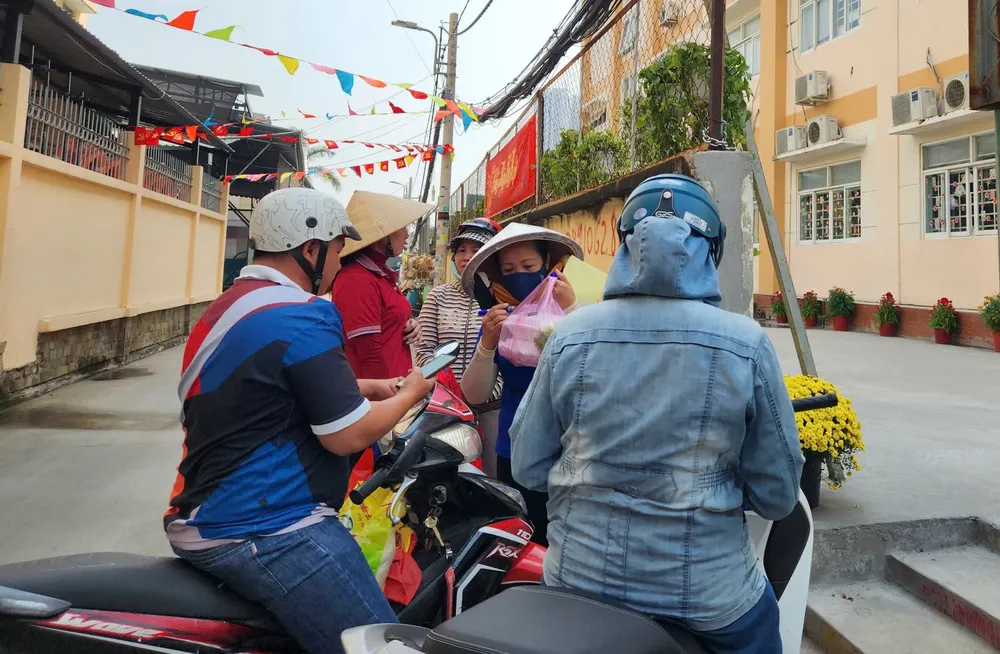 Phụ huynh Trường Tiểu học Nguyễn Văn Hưởng (phường Phú Thuận) mang cơm tới trường cho con vào trưa 29-1 