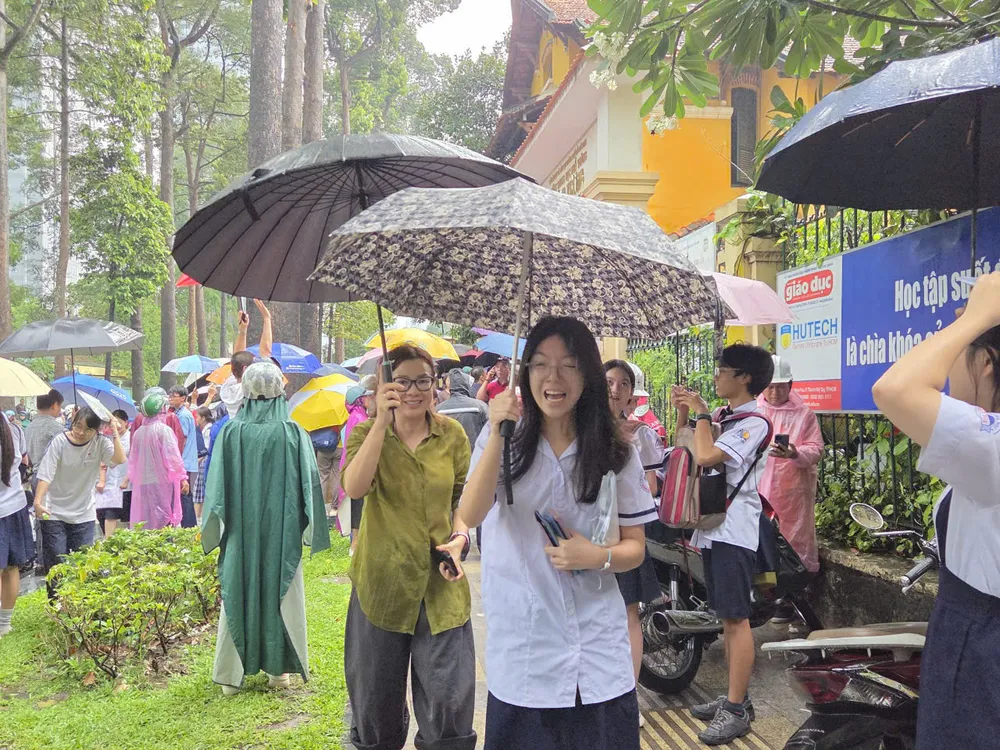 Thí sinh điểm thi THPT Trưng Vương ra về trong cơn mưa tầm tã. Ảnh: THU TÂM