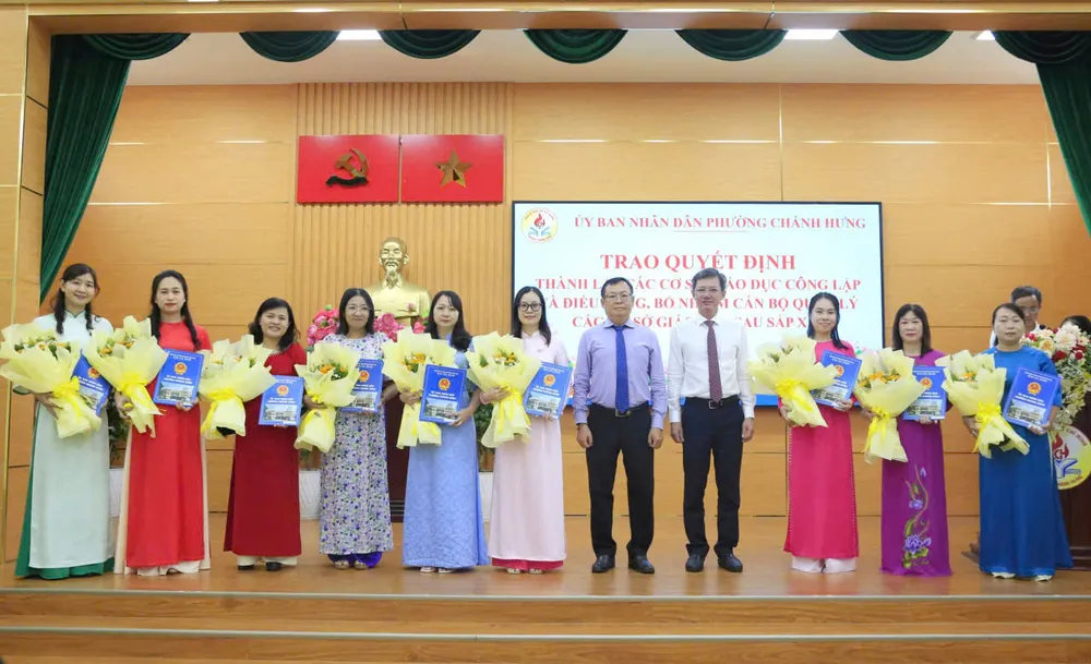 Chủ tịch UBND phường Chánh Hưng Phạm Quang Tú (thứ 7 từ trái sang) trao các quyết định hiệu trưởng, phó hiệu trưởng sau sắp xếp cơ sở giáo dục