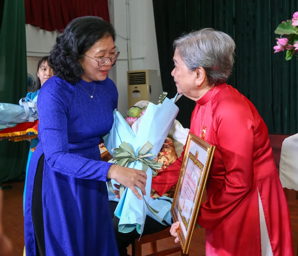 Bí thư Quận ủy quận 5 Huỳnh Ngọc Nữ Phương Hồng tặng hoa chúc mừng đảng viên Nguyễn Thị Minh Hồng, nguyên Ủy viên Trung ương Đảng, nguyên Phó trưởng Ban Tổ chức Trung ương nhận Huy hiệu 60 năm tuổi Đảng. Ảnh: THẢO LÊ