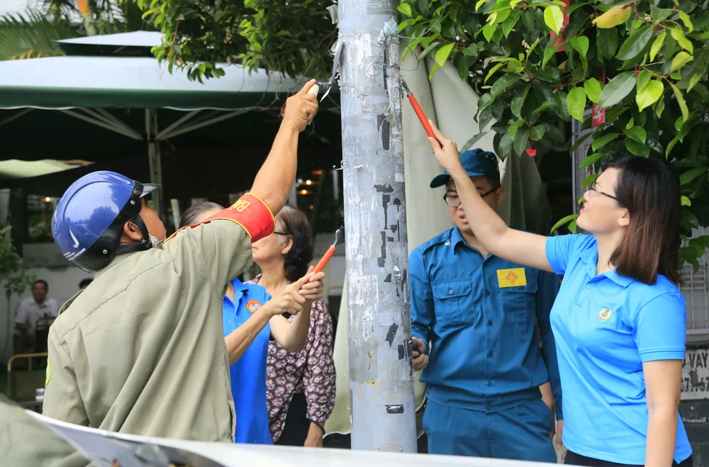 Người dân bóc xóa các quảng cáo sai quy định. Ảnh: UBND quận 8