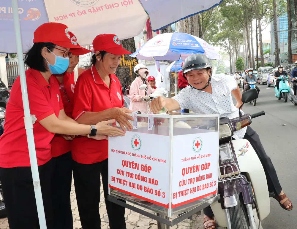 Người dân đóng góp ủng hộ tãi các thùng quyên góp đặt trước trụ sở Hội Chữ thập đỏ TPHCM. Ảnh THÁI PHƯƠNG.JPG