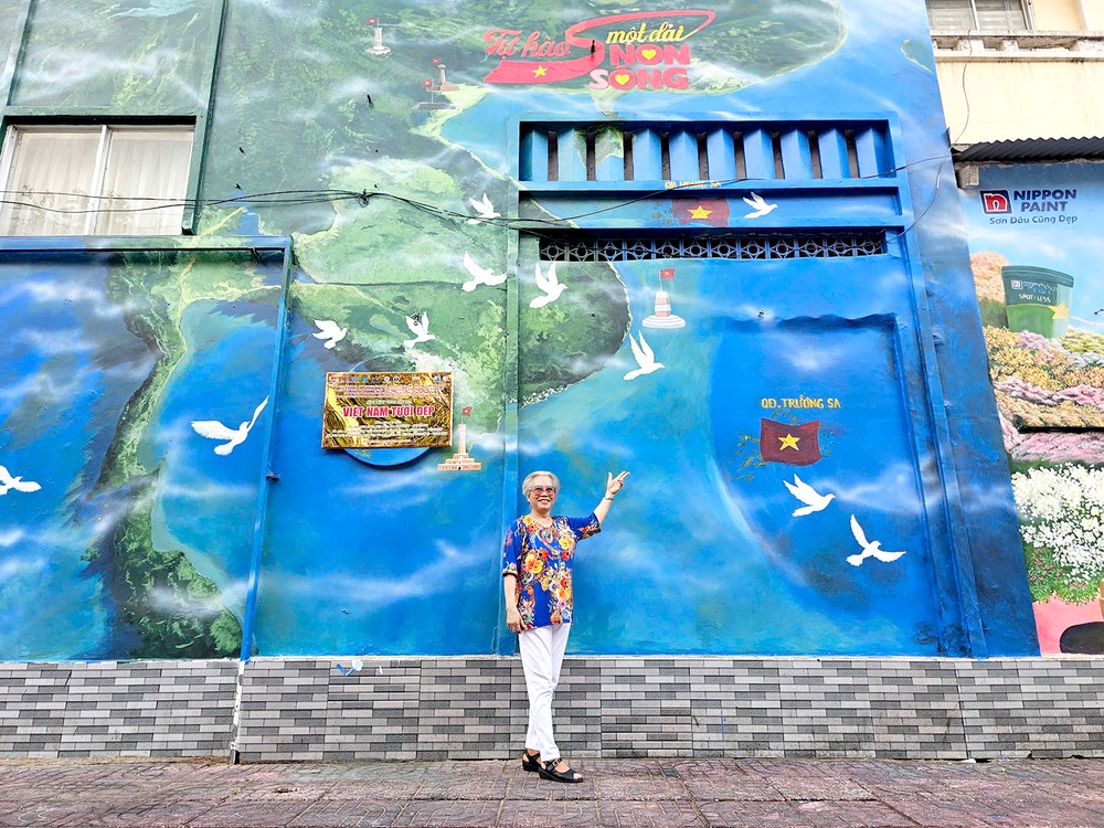 居民高兴地在第一郡阮泰学小学的「美丽越南」壁画前拍照留念。