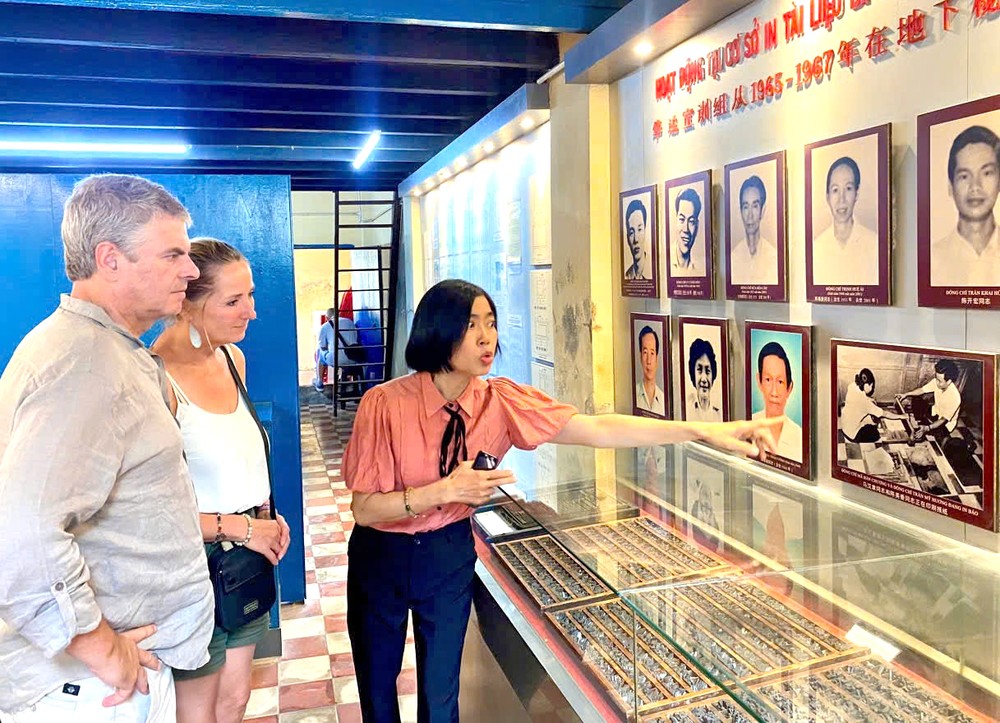 龙长青给游客介绍地下印刷组领导与组员遗照。