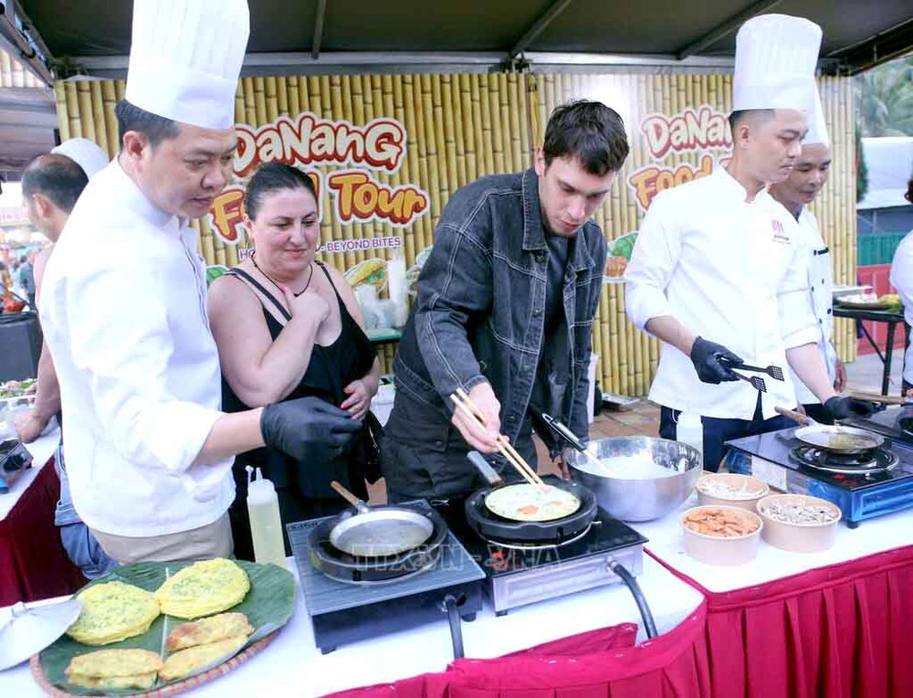 游客在“2025年岘港美食之旅”美食节上体验做煎饼的乐趣。