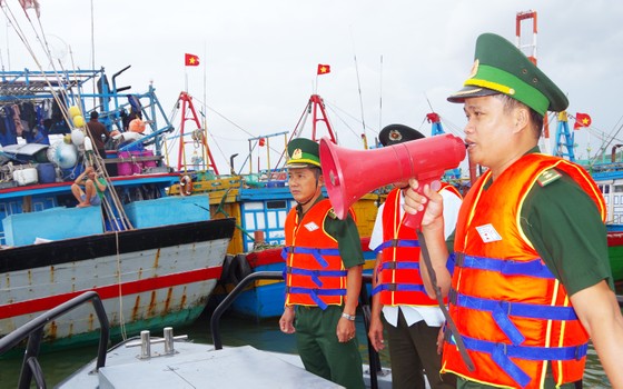 Bộ đội Biên phòng tỉnh Bình Định thông báo cho các ngư dân neo trú tàu thuyền đảm bảo khoảng cách, an toàn trước khi bão đổ bộ. Ảnh: CÔNG CƯỜNG