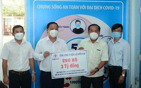 Giám đốc Công ty Điện lực Cà Mau Huỳnh Hữu Quang (thứ 2 từ trái sang), đại diện Tổng Công ty Điện lực miền Nam trao bảng tượng trưng số tiền hỗ trợ cho Ủy ban MTTQ Việt Nam tỉnh Cà Mau. Ảnh: NGỌC HÂN
