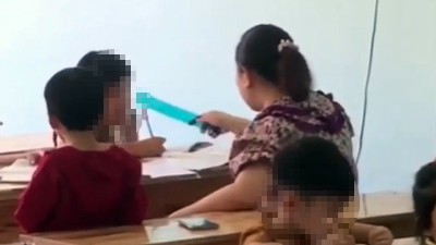 Người phụ nữ dùng thước kẻ đánh học sinh khi đang dạy chữ. Ảnh cắt từ clip