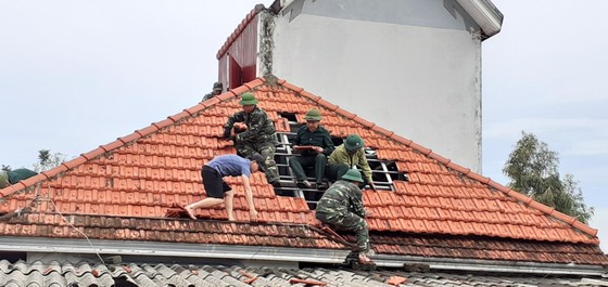 Lực lượng chức năng giúp người dân xã Thịnh Lộc, huyện Lộc Hà lợp lại mái nhà sau thiệt hại do lốc xoáy gây ra