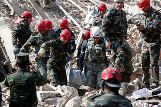 Lực lượng tìm kiếm và cứu hộ mang thi thể từ một đống đổ nát ở TP Ganja - Azerbaijan hôm 11-10. Ảnh: REUTERS