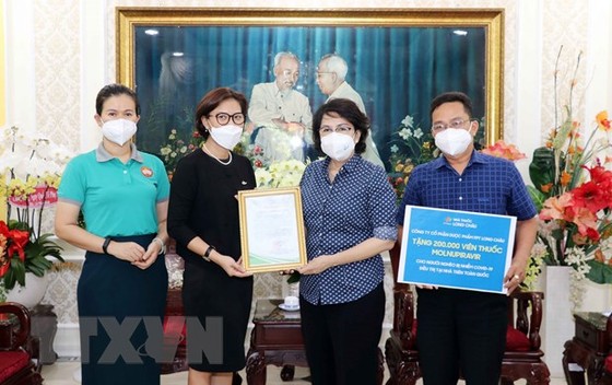Bà Tô Thị Bích Châu, Chủ tịch Ủy ban Mặt trận Tổ quốc Việt Nam TPHCM (thứ hai từ phải sang) trao Thư cảm ơn cho đại diện Công ty Cổ phần Dược phẩm FPT Long Châu. Ảnh: TTXVN