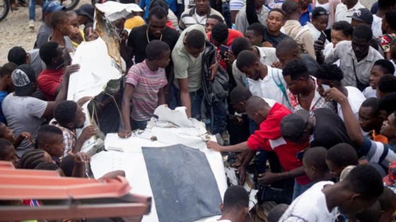 Người dân tập trung quanh đống đổ nát của chiếc máy bay lao xuống một con phố đông đúc tại Haiti. Ảnh: Reuters
