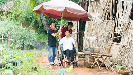 Thành viên CLB chụp ảnh cưới miễn phí hỗ trợ chú rể khuyết tật  di chuyển đến nơi chụp ảnh. Ảnh: HỒNG HÀI